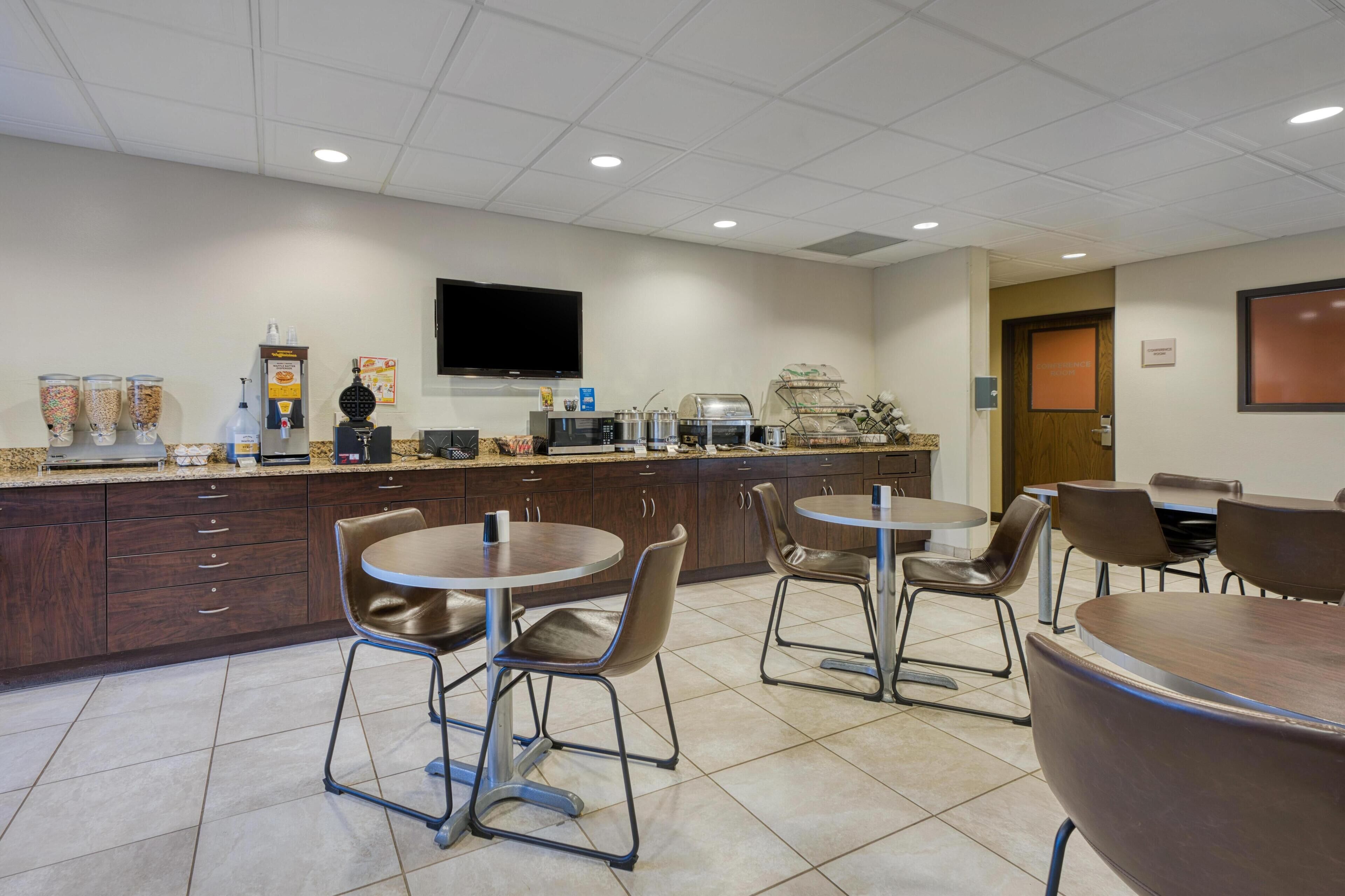 Un espace cuisine moderne équipé d’un téléviseur à écran plat, de machines à café et d’un buffet.