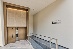 Un ascensor moderno con detalles metálicos y un cartel que indica que es un hotel residencial.