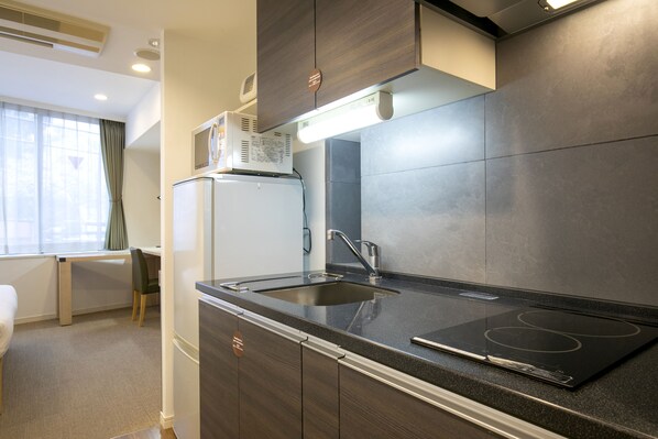 A modern kitchen with a built-in stove, a sink, and a refrigerator. - Residential Hotel B:CONTE Asakusa (Tokyo)