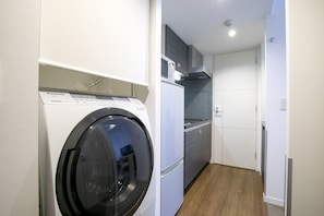 A compact kitchen with a washing machine, a microwave, and a refrigerator.