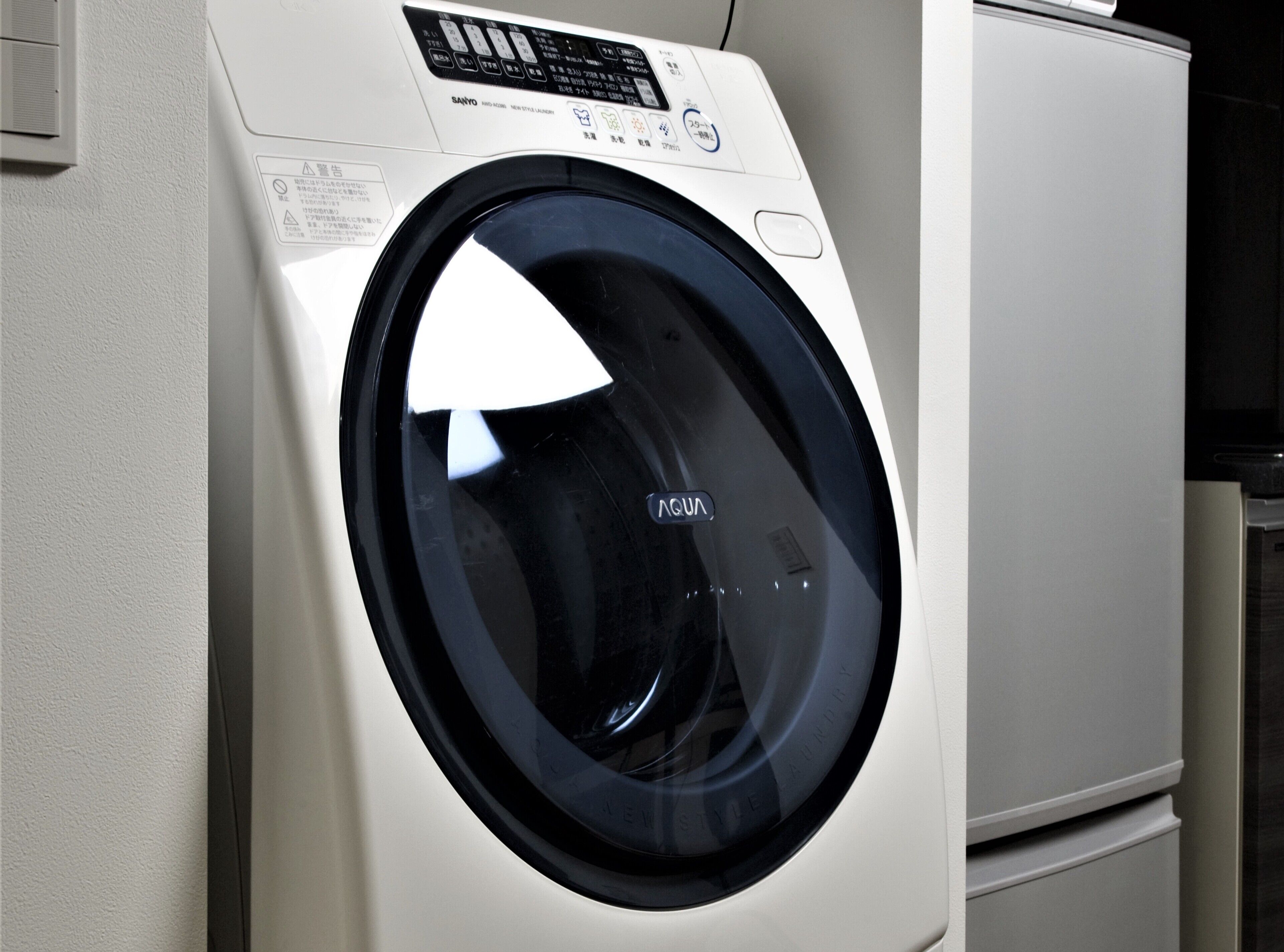 Een voorperspectief van een witte wasmachine met een digitaal bedieningspaneel en een zwarte deur.