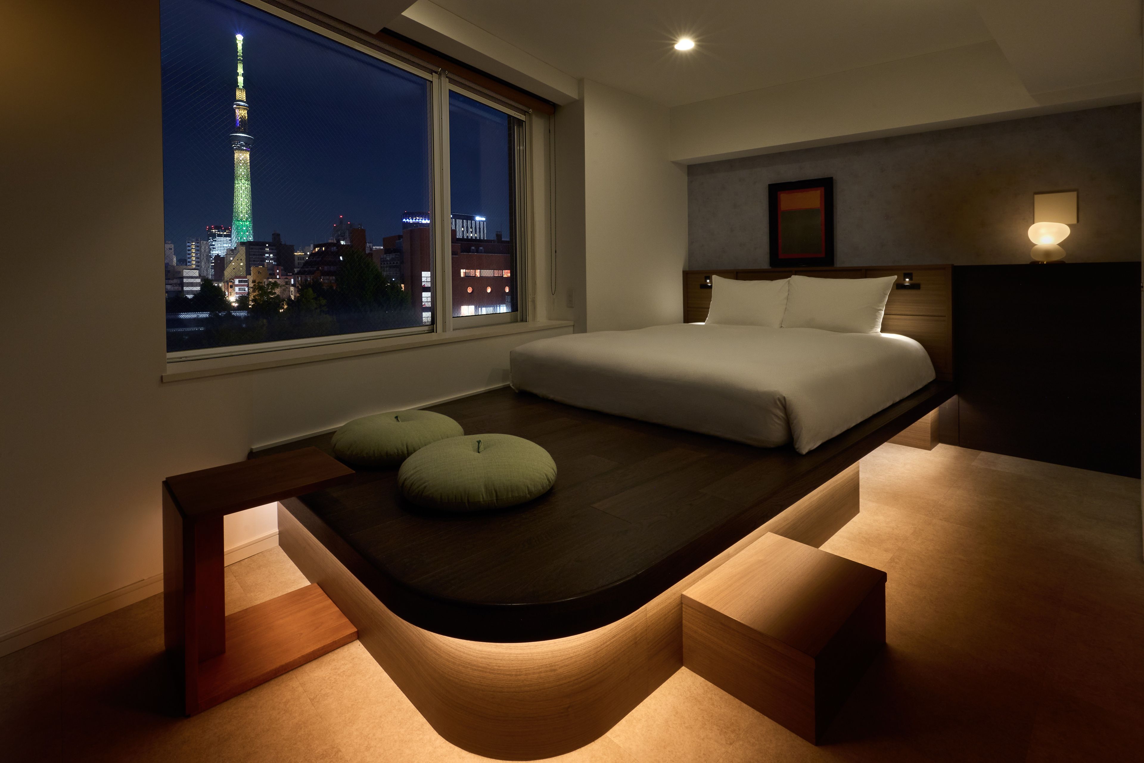 Quarto moderno com cama, janela com vista para a cidade e design único para a mesa de cabeceira.