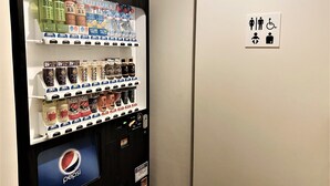 A vending machine with various beverages and a sign indicating a restroom with a wheelchair symbol. - Residential Hotel B:CONTE Asakusa (Tokyo)