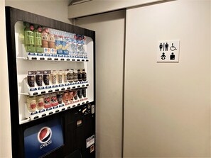 En automattankstation med ett urval av drycker och en skylt som visar var toaletten finns, med en symbol för rullstolsanpassning.