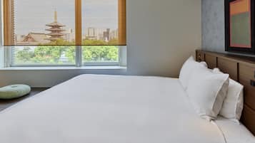 Una habitación de hotel con una cama grande, una ventana con vistas a la arquitectura tradicional y una obra de arte moderna en la pared.