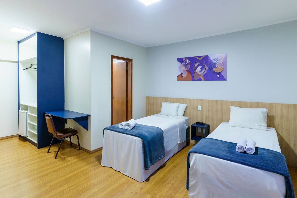 Une chambre d’hôtel avec deux lits, un bureau et une chaise.