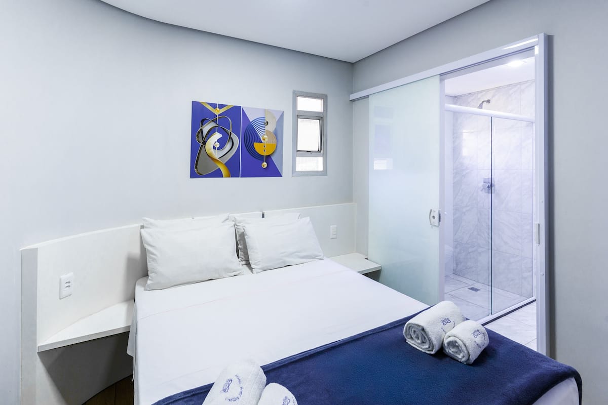 Une chambre d’hôtel avec un lit, une fenêtre, une douche et un tableau au mur.