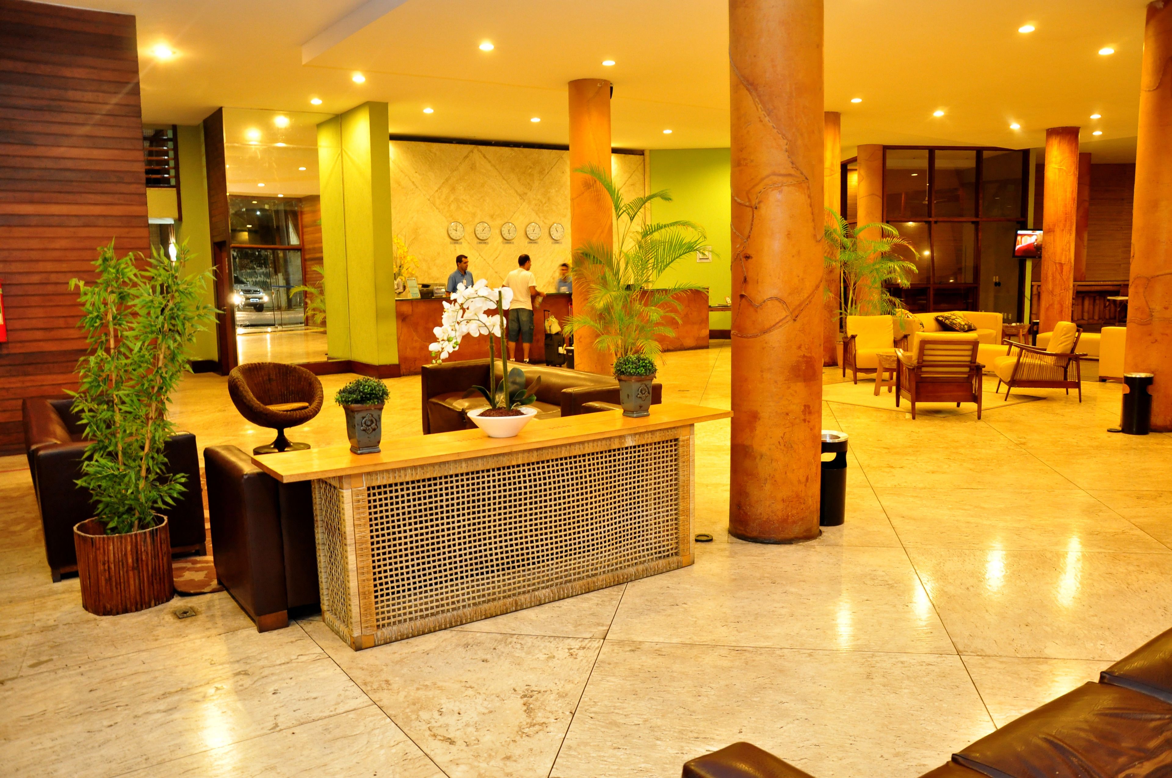 A hotel lobby with a reception desk, seating area, and large pillars.