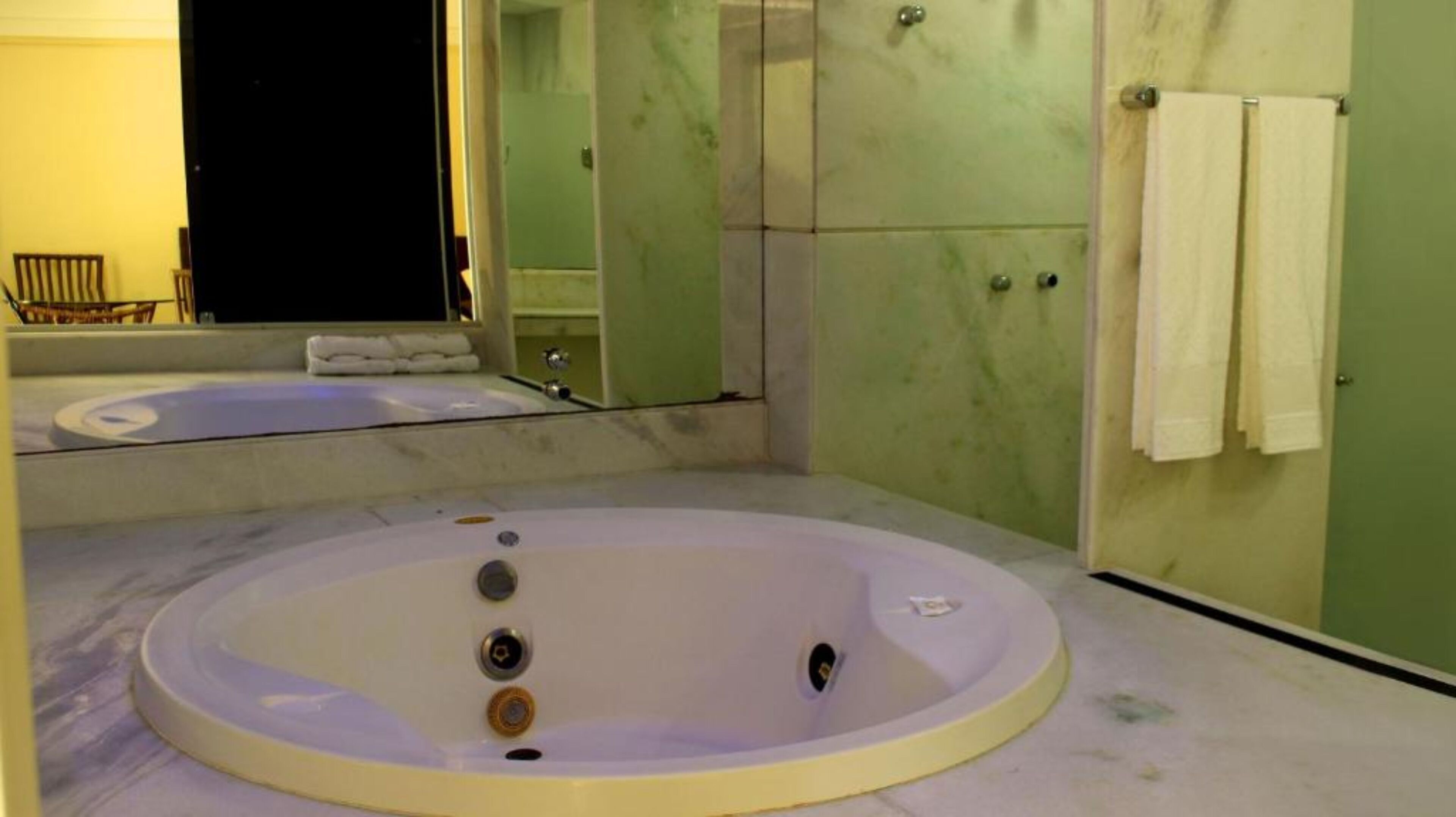 Une salle de bain avec une grande baignoire, un miroir et un porte-serviettes.