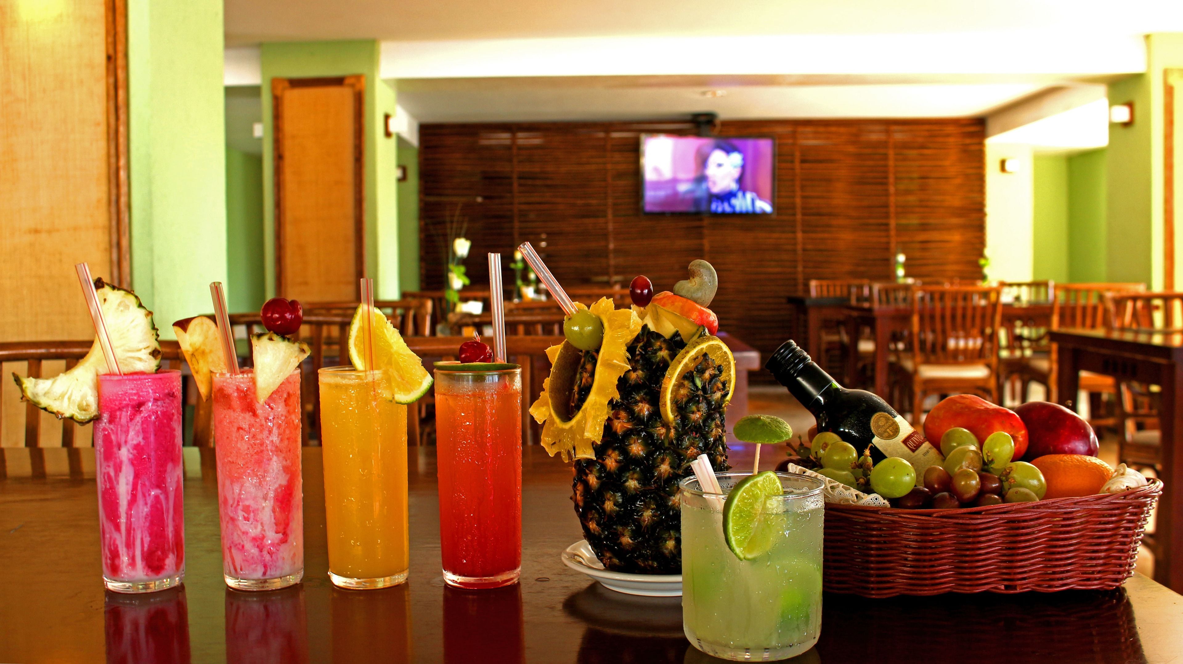 Zona de bar con diversas bebidas y una cesta de frutas.