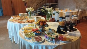 A buffet table with various food items and beverages, surrounded by chairs and tables. - Hotel Alves (Braga)