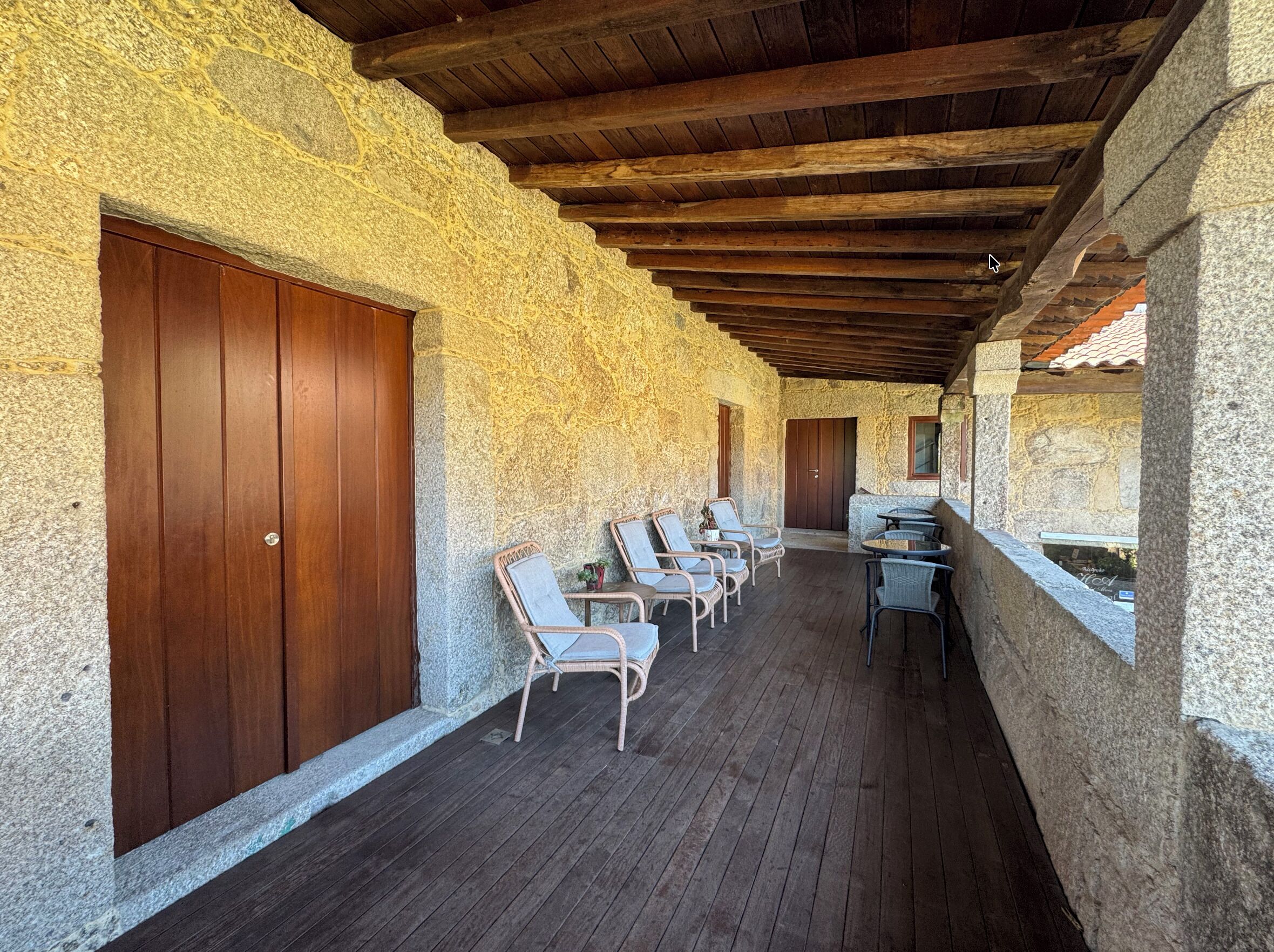 Un espacio al aire libre cubierto con paredes de piedra, puertas de madera y asientos.