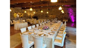 A banquet hall with long tables set for a formal event, featuring white chairs, gold tableware, and hanging pendant lights. - Hotel Alves (Braga)