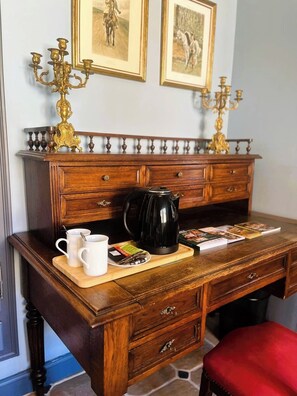 Un escritorio de madera con una cafetera, dos tazas y una bandeja con libros y un plato de aperitivos.