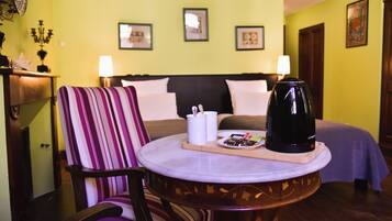 Een hotelkamer met een bed, een stoel, een ronde tafel met dienblad, een koffiezetapparaat en wandlampen.
