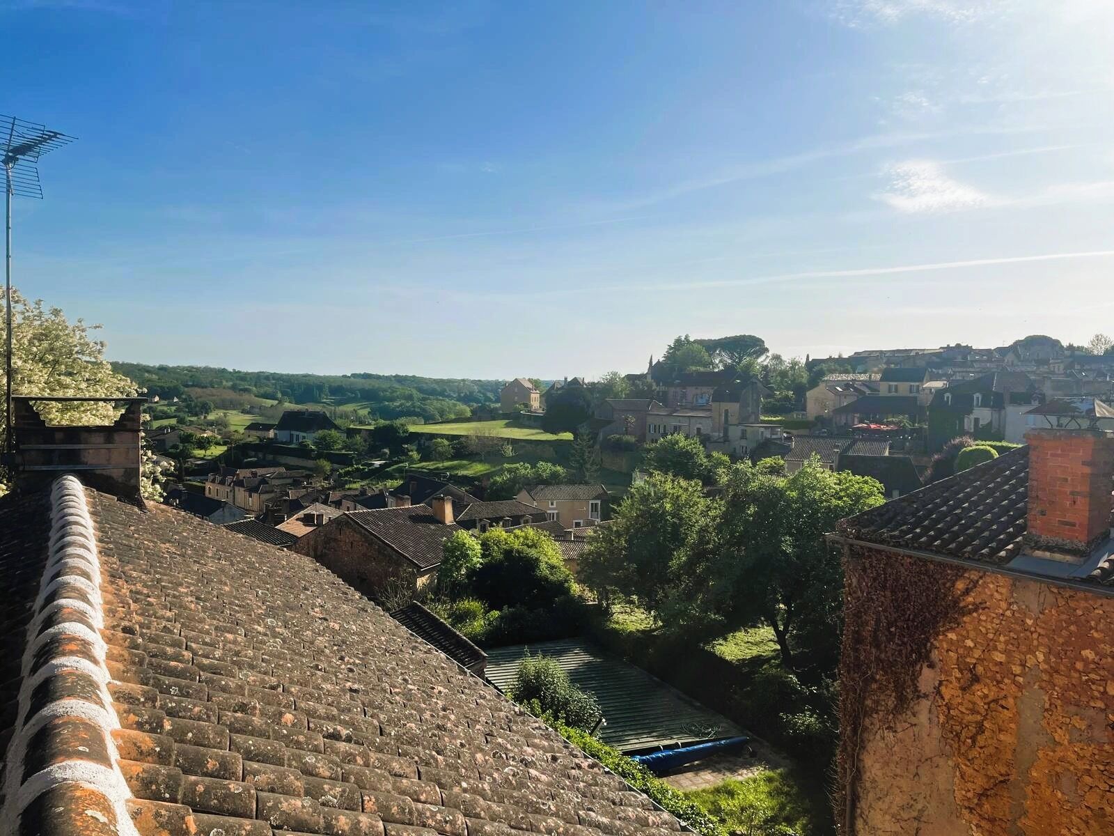 A town with historic buildings, a clear sky, and a view of the countryside.