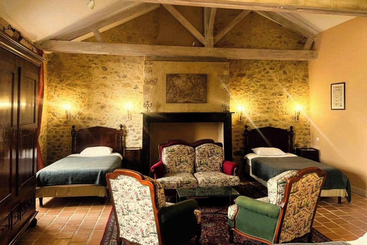 Een kamer met twee bedden, een open haard en een stenen muur.