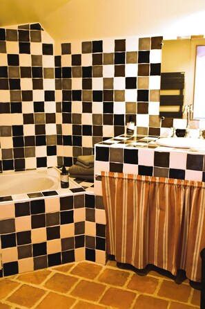 Un baño con pared de baldosas a cuadros, una bañera, un lavamanos y una cortina a rayas.