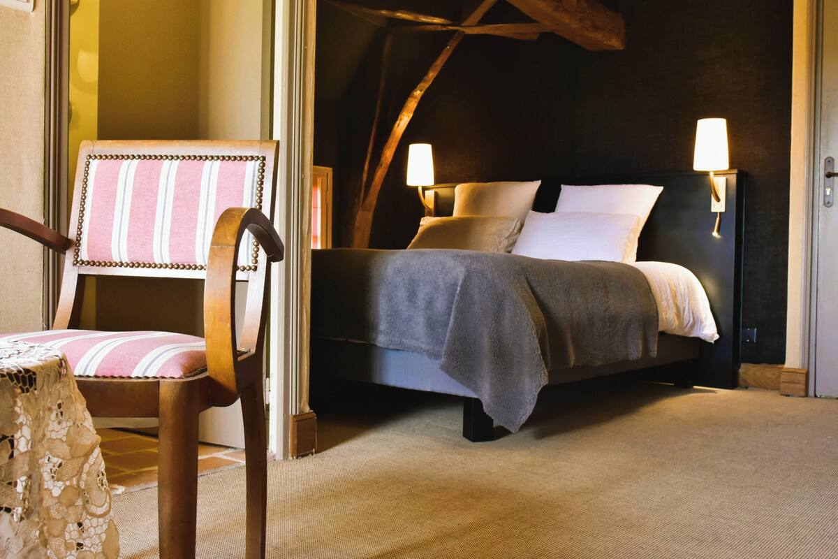 Een slaapkamer met een bed, twee bedlampen, een stoel en een tafel.
