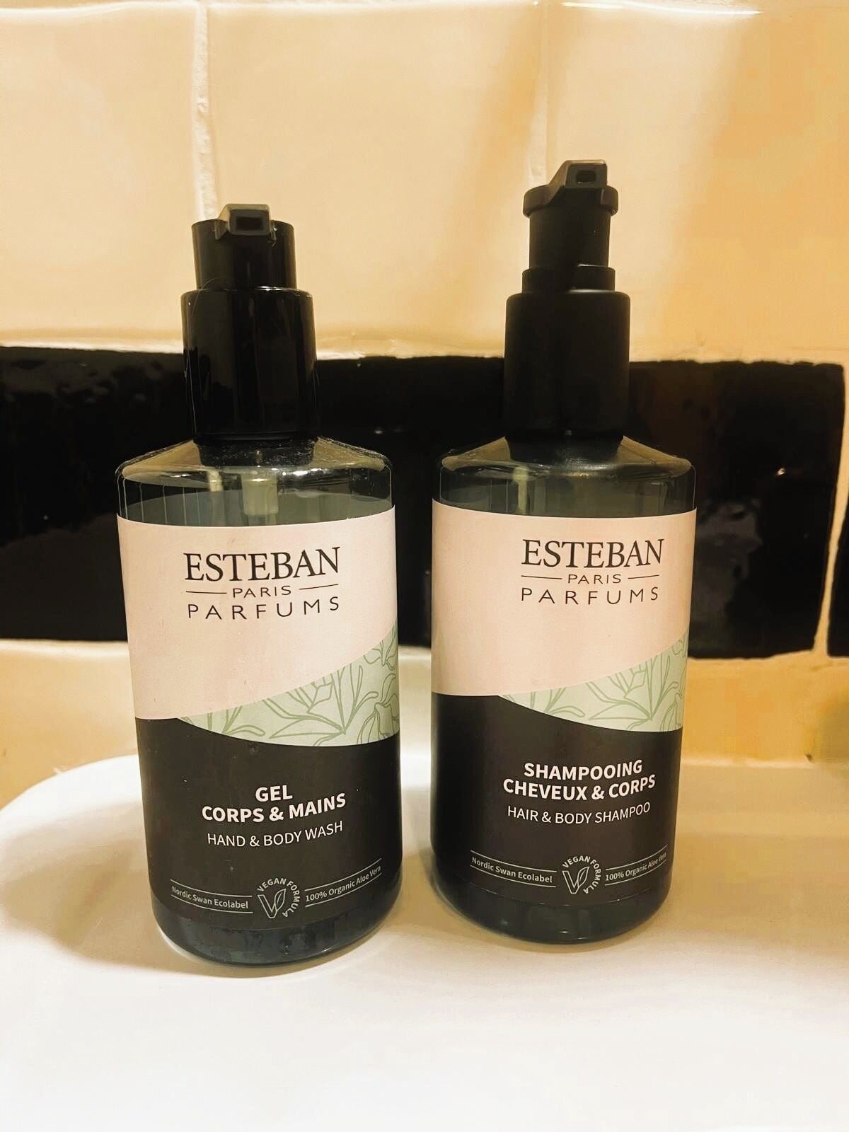 Kaksi pulloa Esteban Paris Parfums -merkkiä olevaa hiusten- ja vartalonpesuainetta valkoisella alustalla.