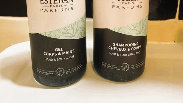 Two bottles of Esteban Paris Parfums hair and body shampoo on a white surface.