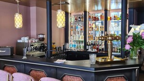 Un espace bar comprenant un comptoir, des tabourets de bar et une variété de bouteilles et de verres.