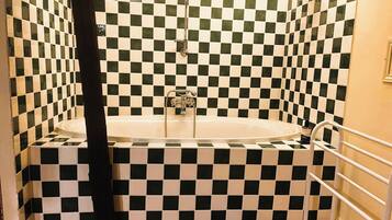 A bathroom with a checkered tile wall, a bathtub, and a shower area.