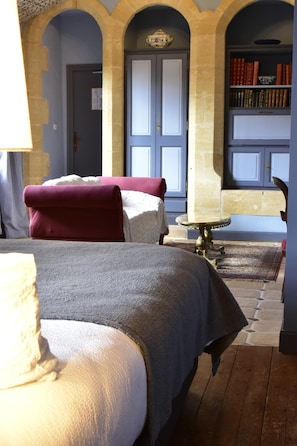 Una habitación con dos camas, una mesita y una estantería.