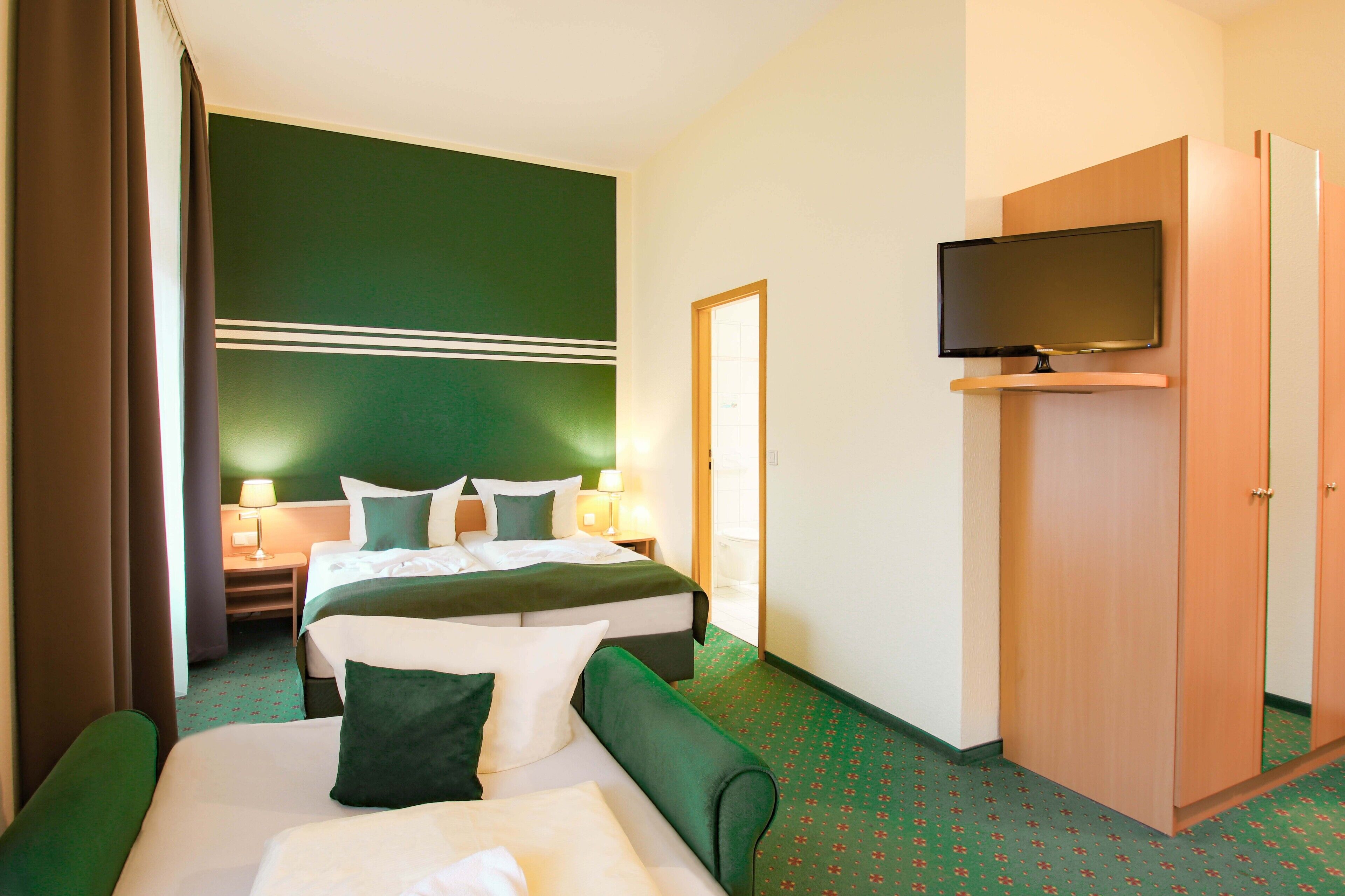 A hotel room with two beds, a television, a wardrobe, and a nightstand with lamps.