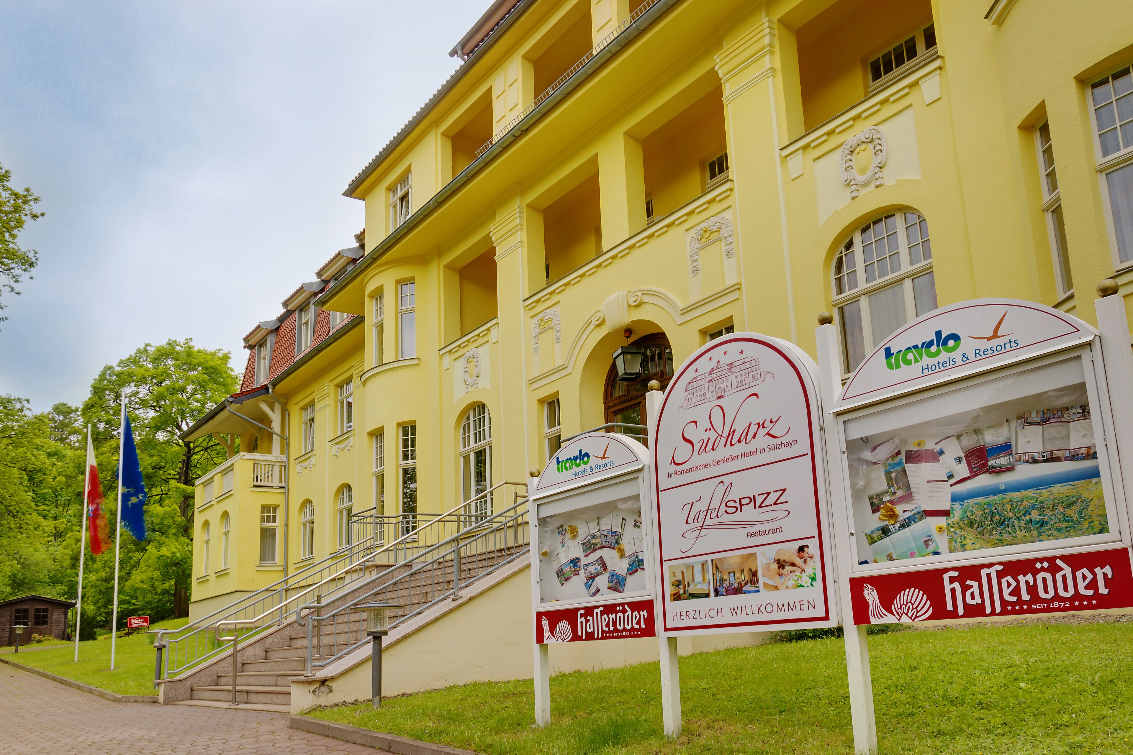 A yellow building with a staircase leading to a balcony, signs for 'trado Hotels & Resorts', 'Südlich', 'TafelSPSS', and 'Hafneröder'.