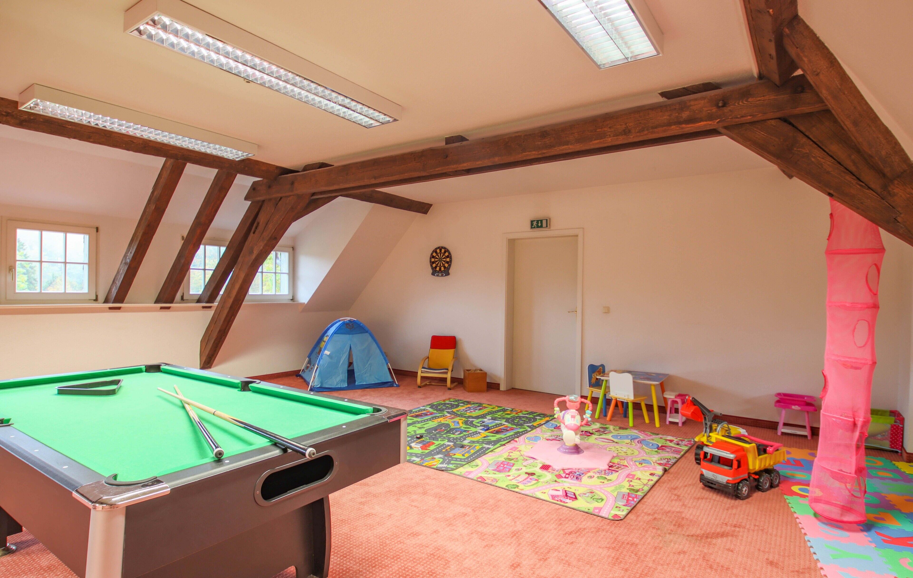 A children's playroom with a pool table, colorful play mats, and toys.