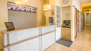 Un espace d’accueil comprenant un comptoir, une horloge et un panneau indiquant les services disponibles.