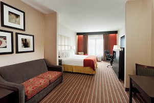 Una habitación de hotel con cama, sofá, escritorio y televisor.