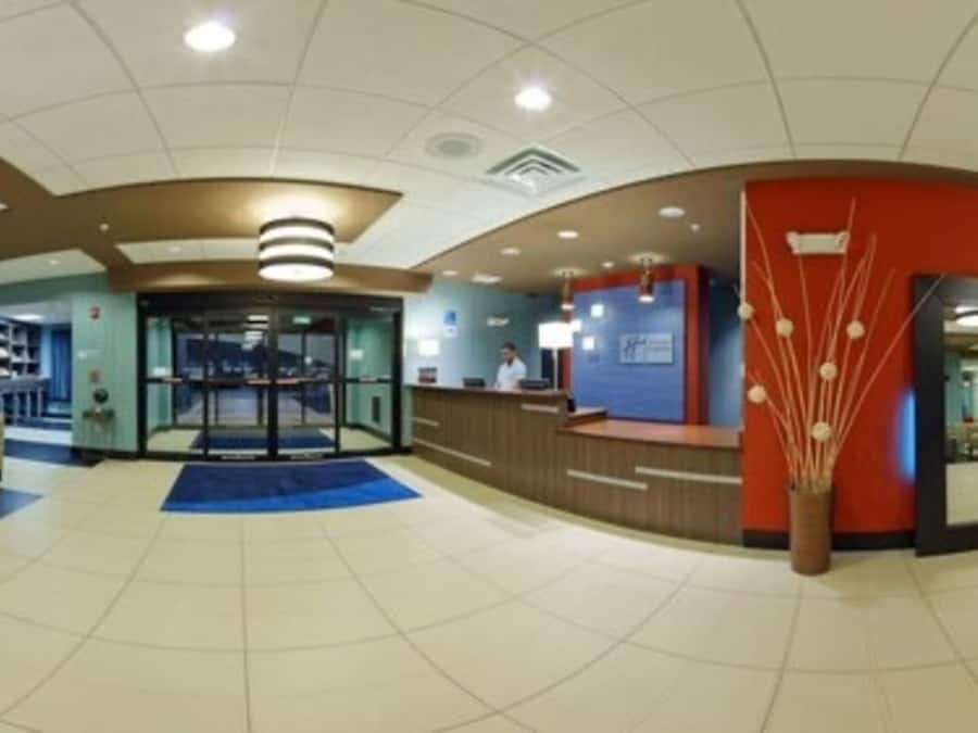 A hotel lobby with a reception desk, seating area, and a glass door entrance.