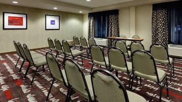 A conference room with rows of chairs, a table, and two framed pictures on the wall.