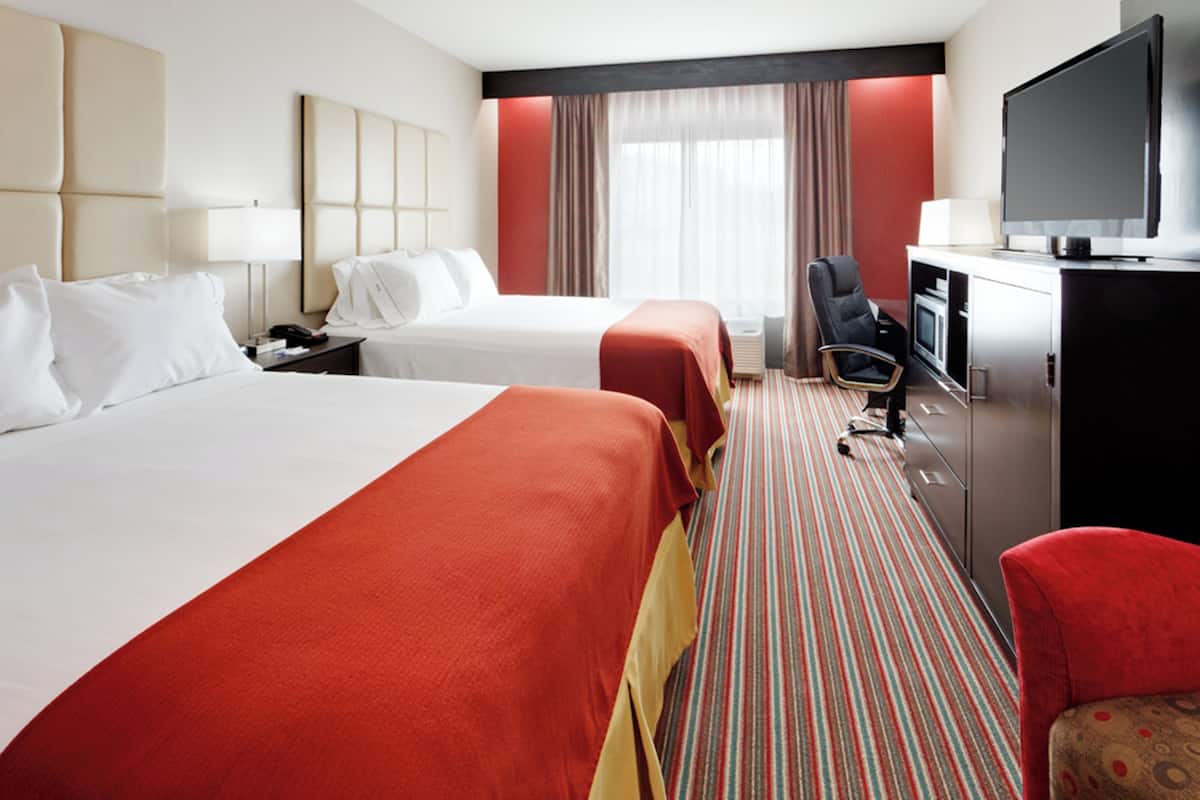 A hotel room with two beds, a TV, a desk, and a chair.