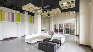A spacious living area with a sectional sofa, a black ottoman, and a coffee table. A ceiling fan and recessed lighting are visible. - Malin Patong Hotel (Patong)