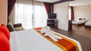A hotel room with a large bed, a television, and a second bed in the background. - Malin Patong Hotel (Patong)