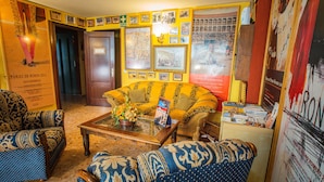 Een gezellige woonkamer met gestreepte banken, een bijzettafeltje en een boekenplank vol boeken.