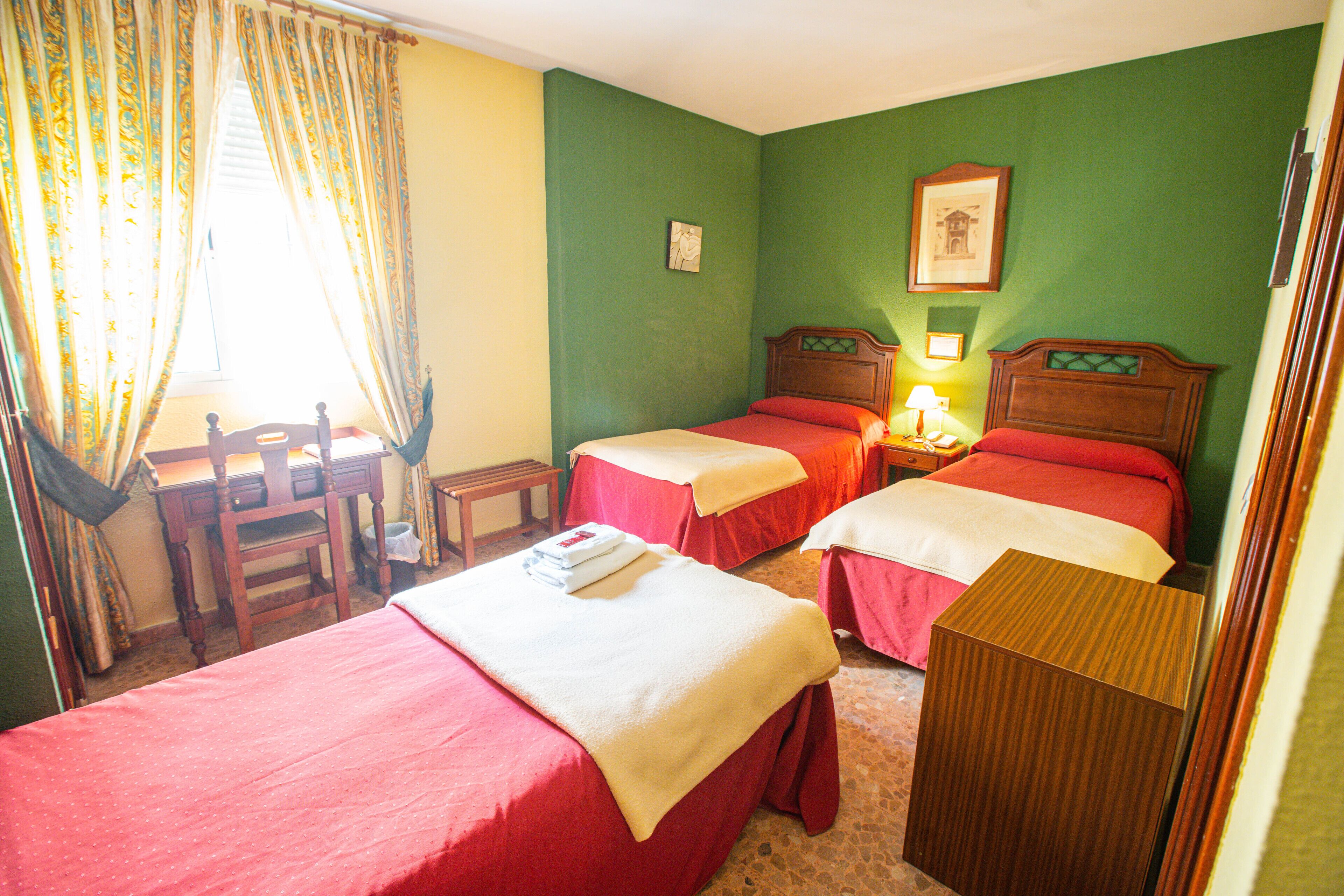 Ein Hotelzimmer mit zwei Betten, einem Schreibtisch und einem Stuhl.