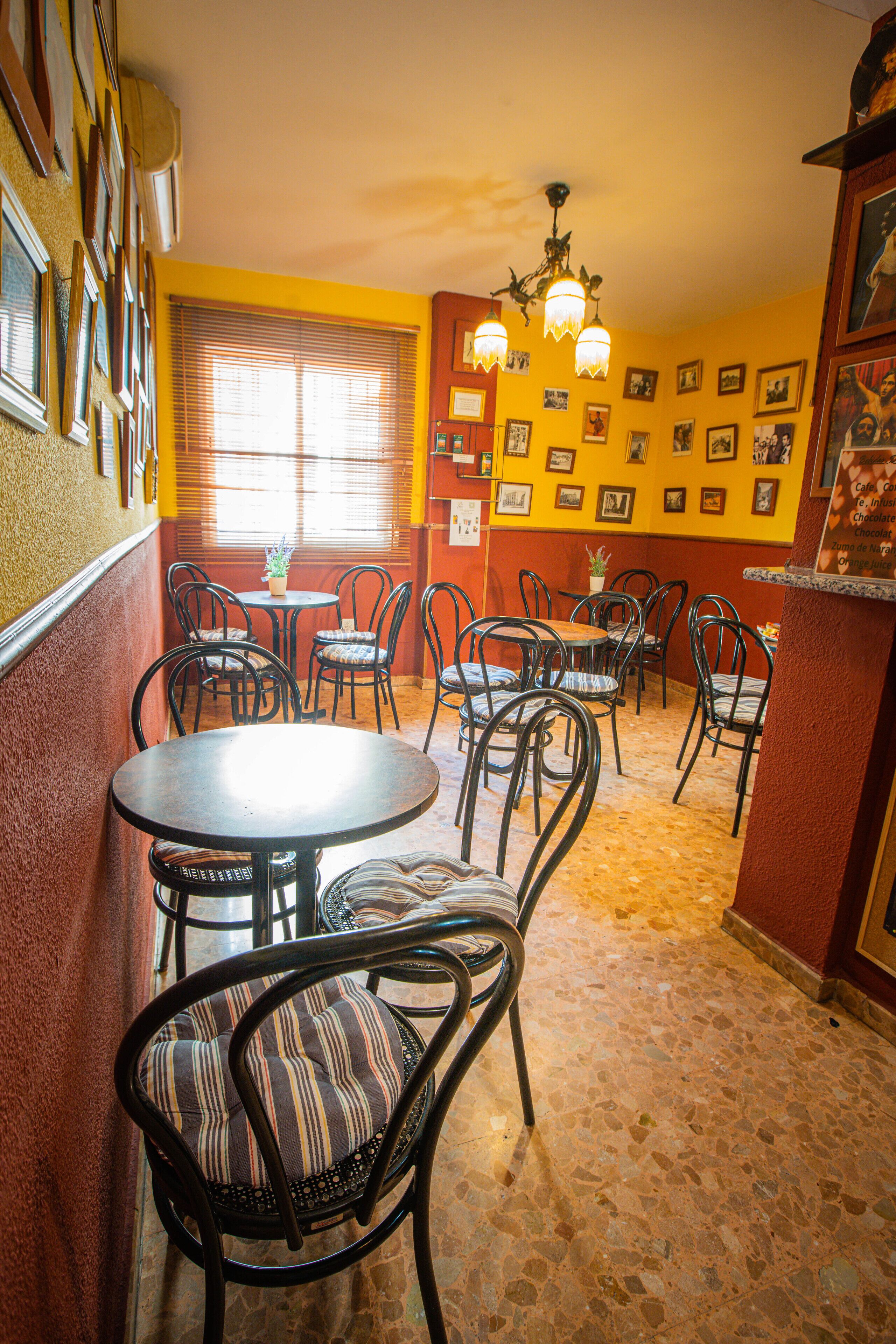 A dining area with round tables and chairs, a chandelier, and framed pictures on the walls.