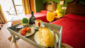 Een ontbijtplateau met croissant, sinaasappelsap en koffie in een hotelkamer met een bed en uitzicht.