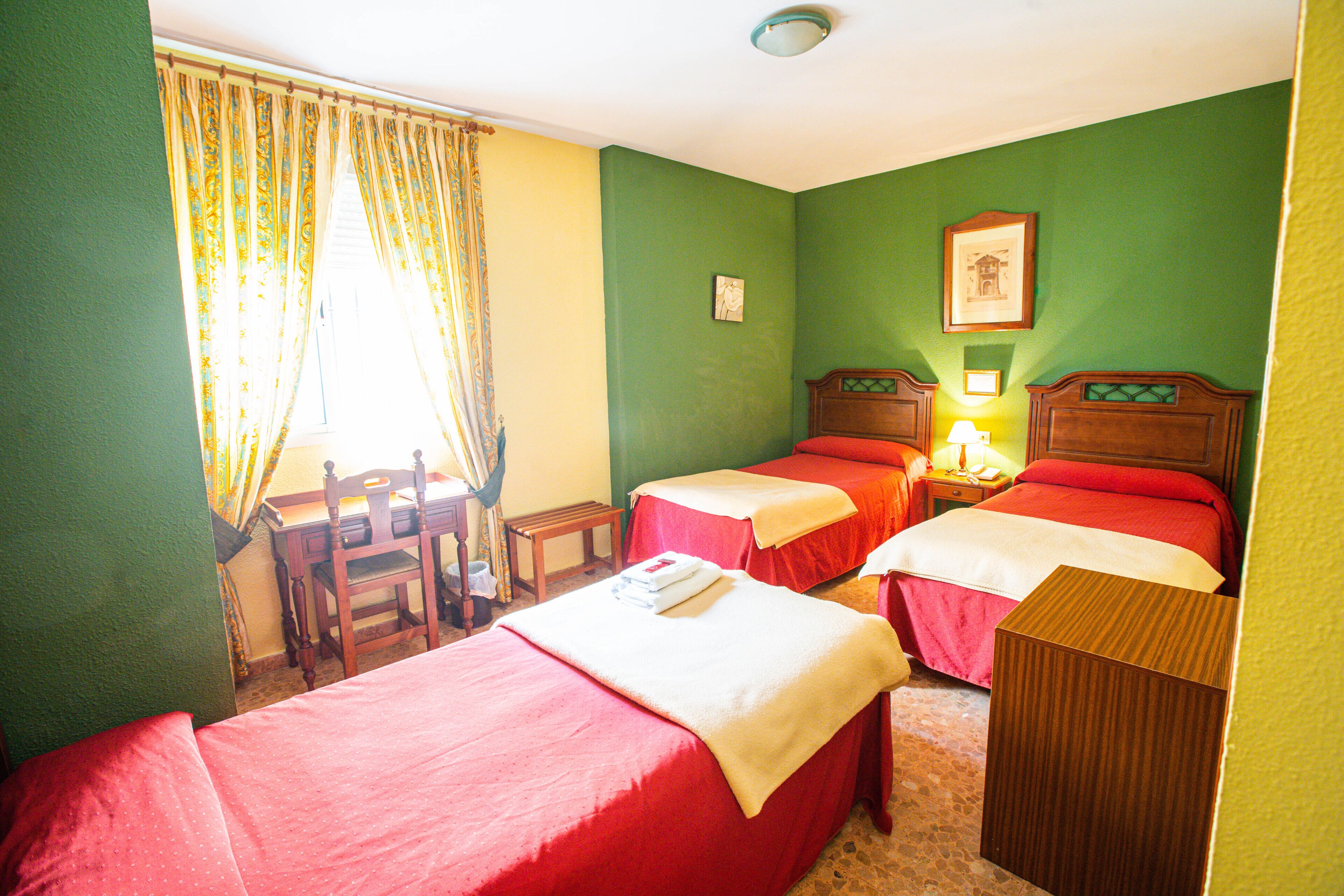 A room with two beds, a desk, and a chair.