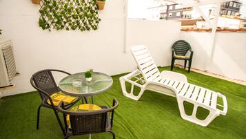 A patio with a round table, two lounge chairs, and a potted plant.