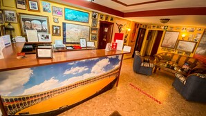 Een receptie met een balie, ingelijste foto's, een groot muurschildering, een bank en een bijzettafeltje.