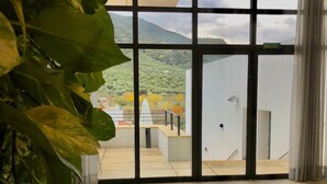 Amplia habitación con ventanas grandes que ofrecen vistas a un paisaje montañoso.
