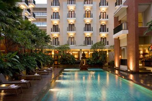 Un hôtel doté d’une piscine, de chaises longues et d’une fontaine.