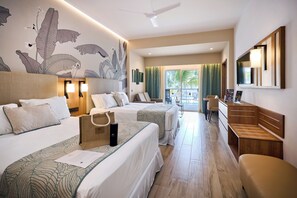 A hotel room with two beds, a desk, a chair, a large mirror, and a view of the outdoor area.