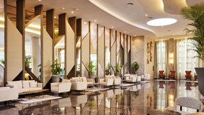 A spacious lobby with a polished marble floor, modern seating arrangements, and large windows allowing natural light.