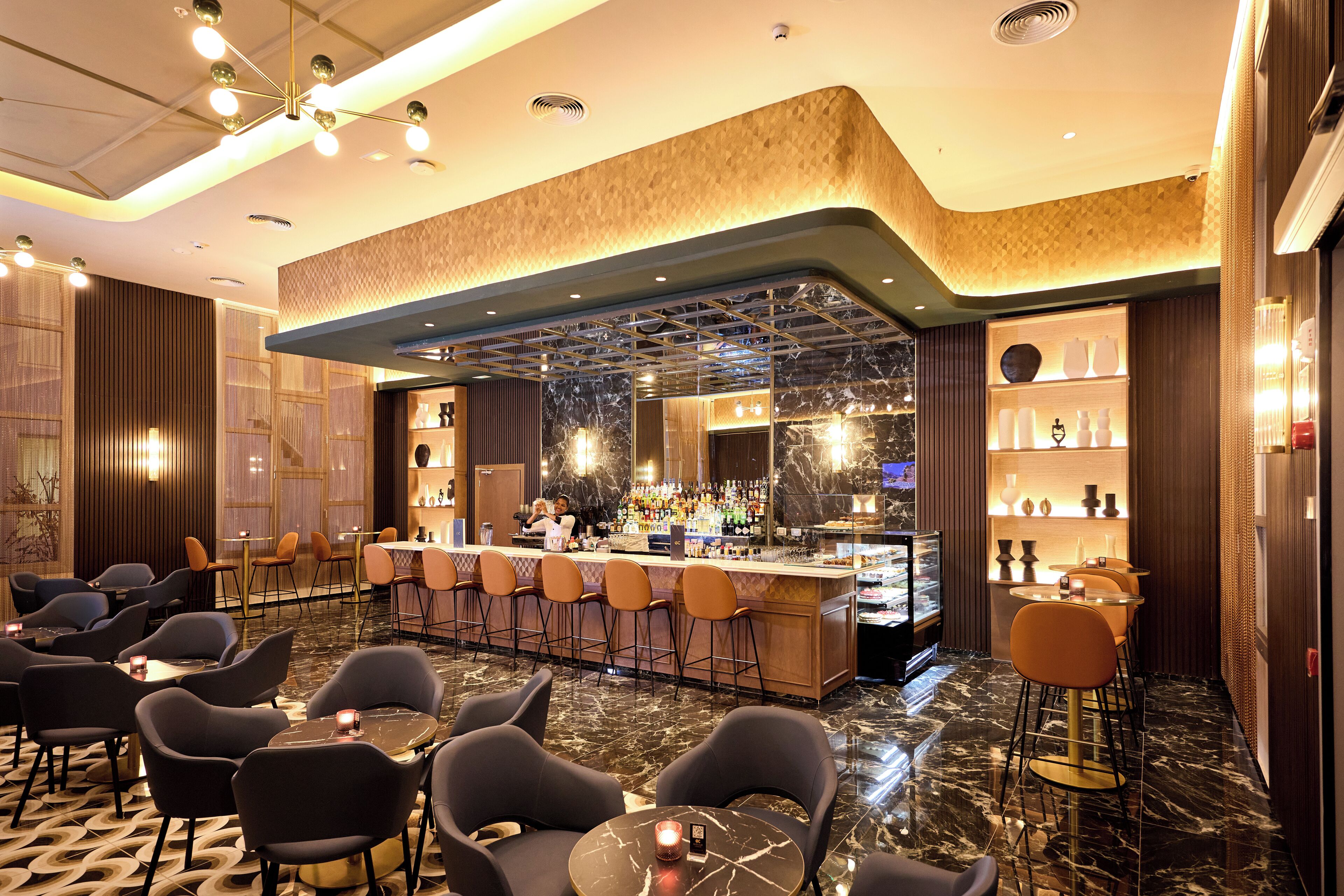 Een moderne bar met een marmeren vloer, barstoelen en een goed verlichte toog.